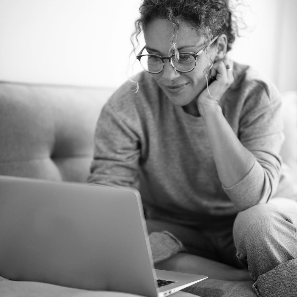 woman looking at a computer screen at home on the couch